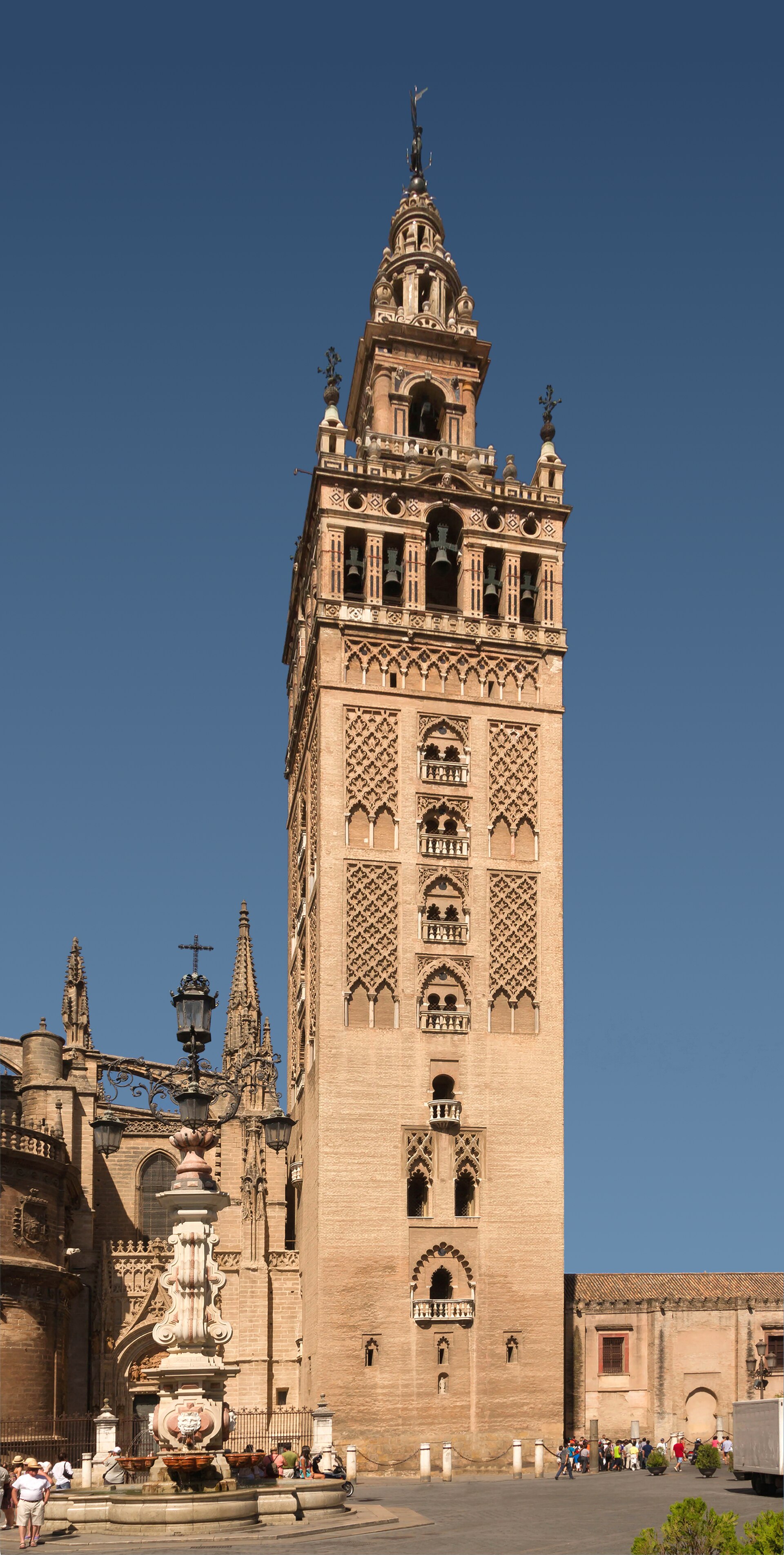 La Giralda desde el patio, con fuente, fragmento de la catedral gótica y visitantes, Sevilla.
