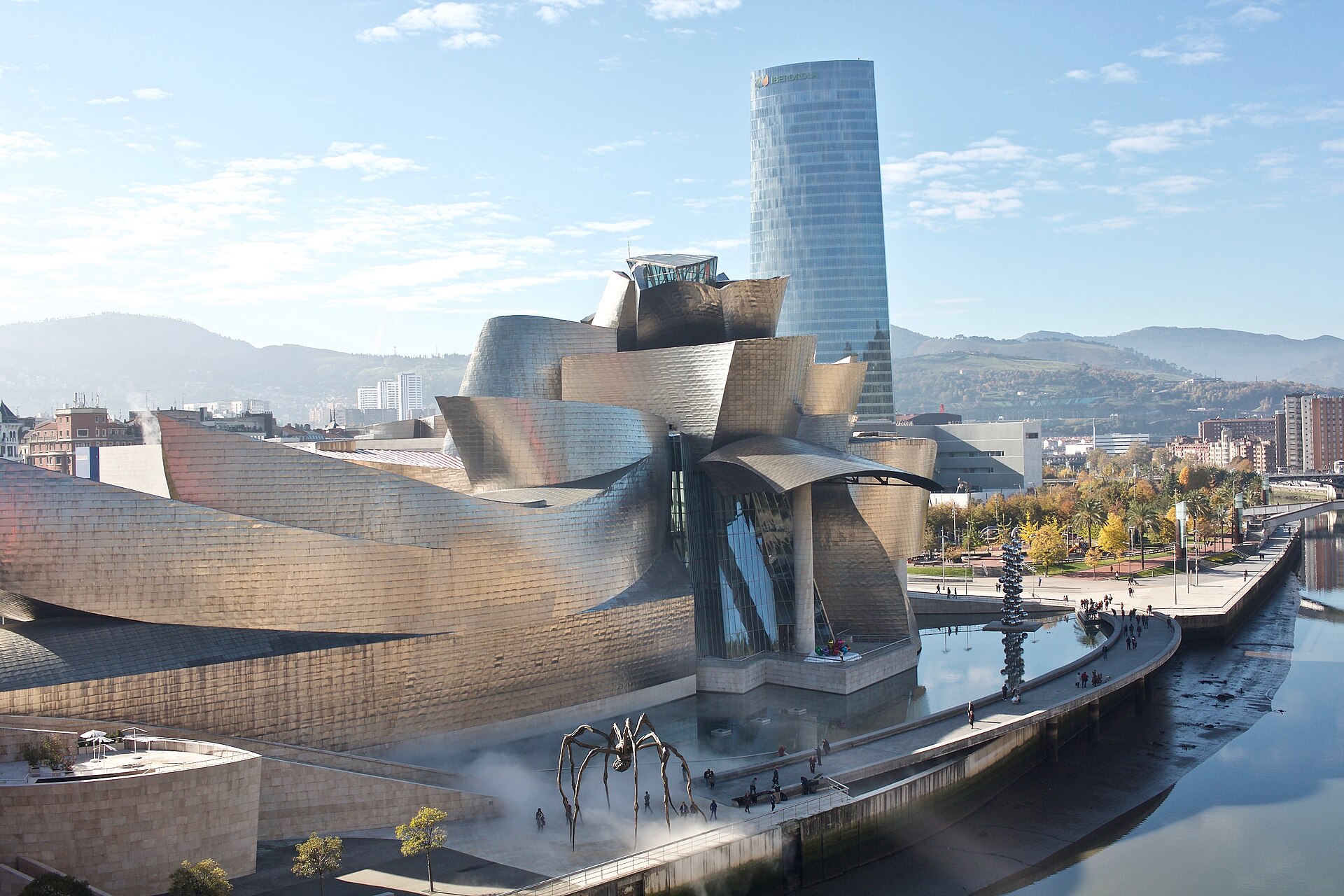 Museo Guggenheim Bilbao junto al Nervión, con la araña Maman y la torre Iberdrola al fondo.